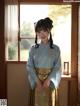 A woman in a blue and green kimono standing by a window.