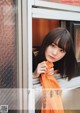 A woman in an orange scarf leaning against a window.