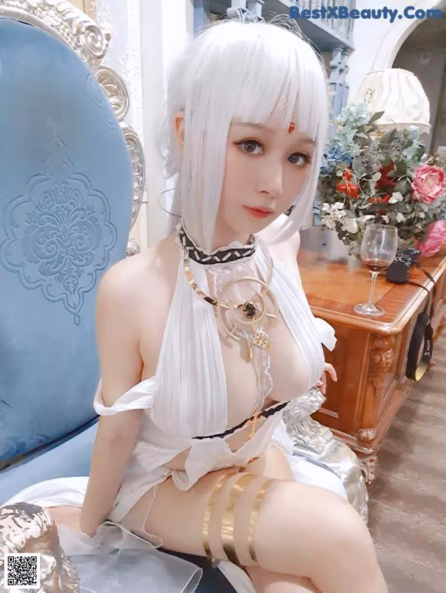 A woman in a white dress sitting on a blue chair.