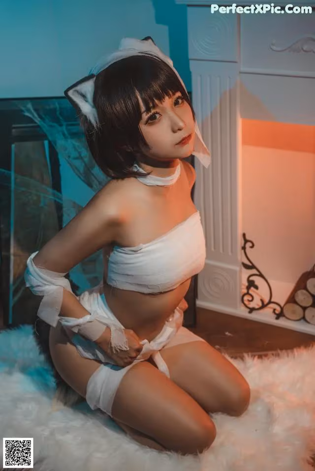 A woman in a white cat costume sitting on a white rug.