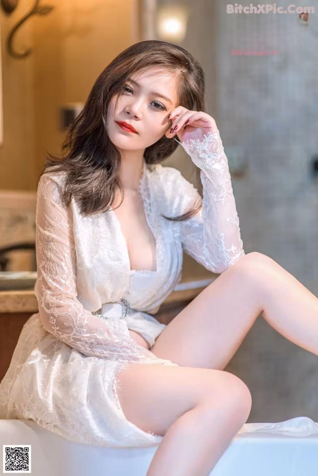 A woman in a white robe sitting on a bathtub.