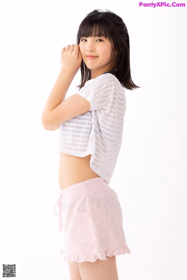 A young woman wearing a white shirt and pink shorts.