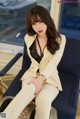 A woman in a white suit sitting on a blue chair.