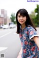 A woman in a blue dress standing on the side of a road.