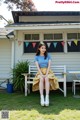 A woman sitting on a bench in front of a house.