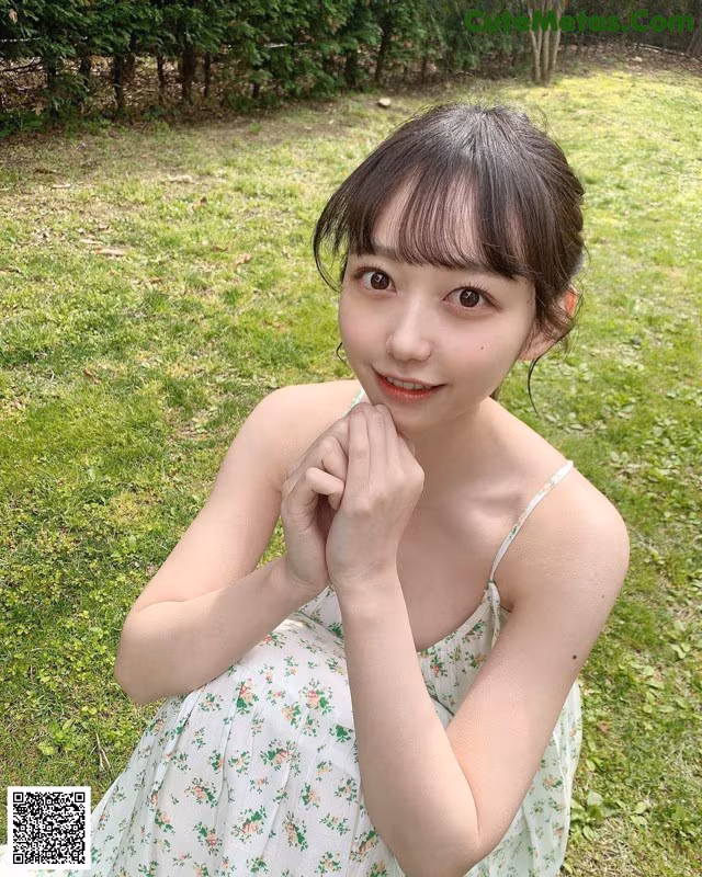 A woman in a white dress sitting in the grass.