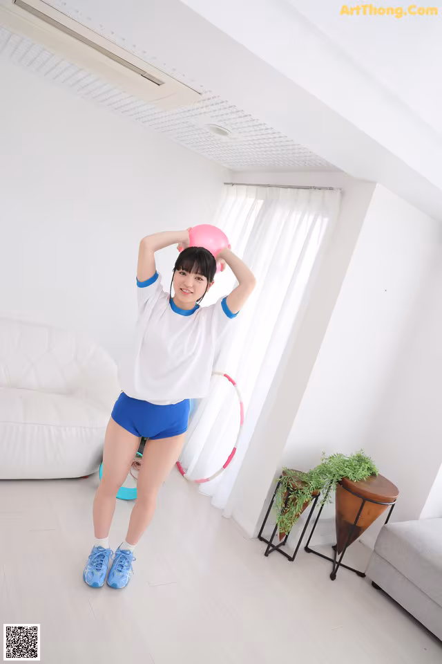 A woman in a white shirt and blue shorts holding a pink ball.