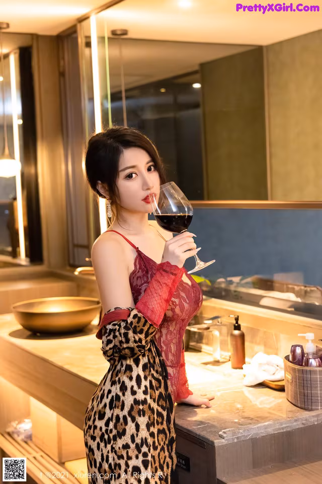 A woman in a leopard print dress holding a glass of wine.