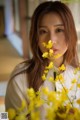 A woman holding a vase of yellow flowers in her hand.