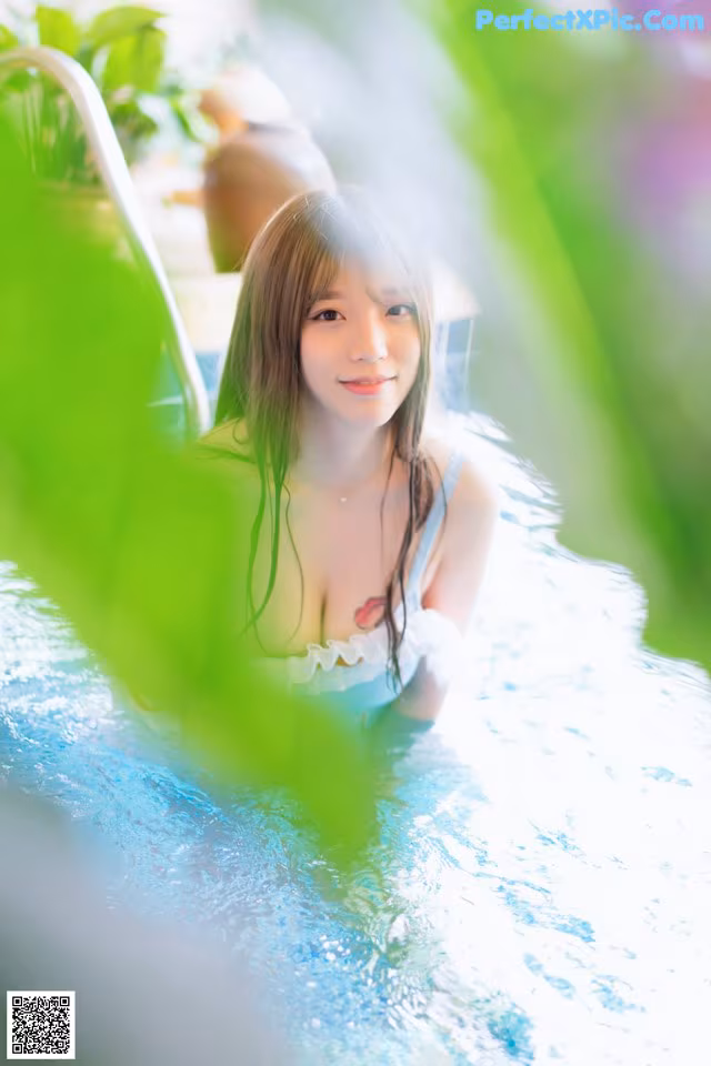 A woman in a white dress is sitting in a pool.