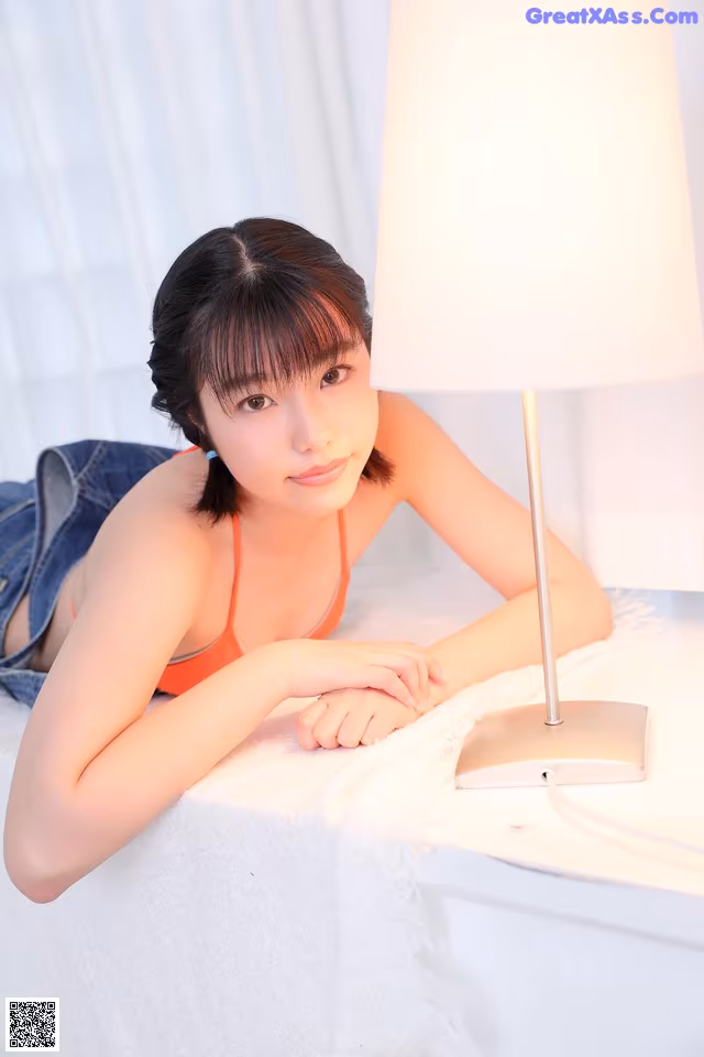 A woman laying on a bed next to a lamp.