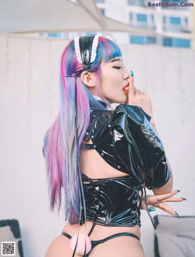 A woman with purple and blue hair wearing a black latex outfit.