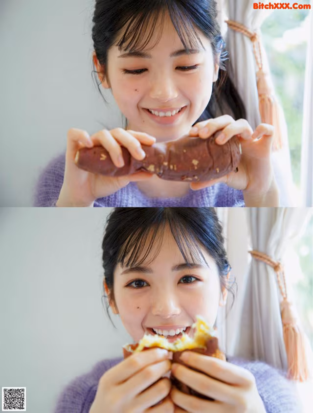 A woman eating a piece of food in front of a window.