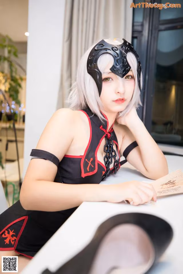 A woman in a black and red outfit sitting at a table.