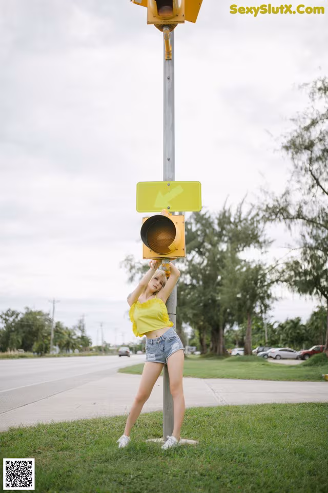 A woman standing next to a traffic light on a pole.