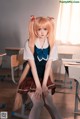 A girl in a school uniform sitting on a desk.