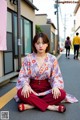 A woman sitting on the ground in a kimono.