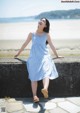 A woman in a blue and white striped dress sitting on a wall.