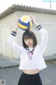 A woman in a school uniform holding a volleyball.