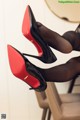 A pair of black and red high heels on a chair.