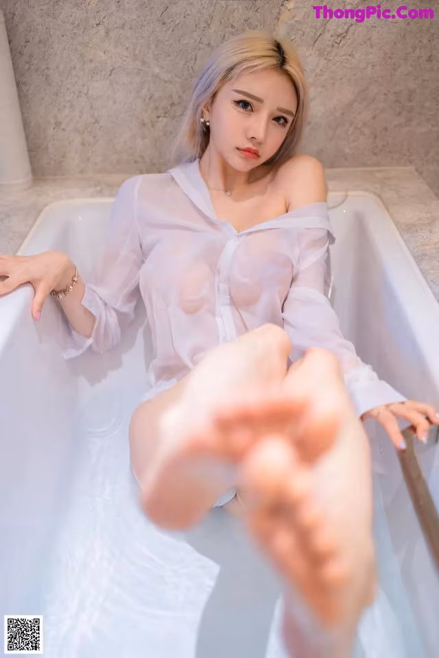 a woman sitting in a bathtub with her feet up